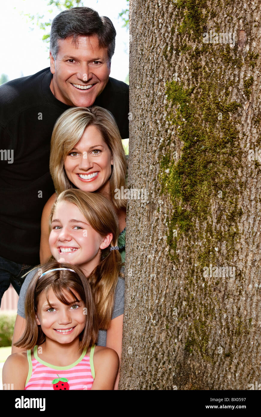 Sorridente famiglia caucasica vicino a tronco di albero Foto Stock