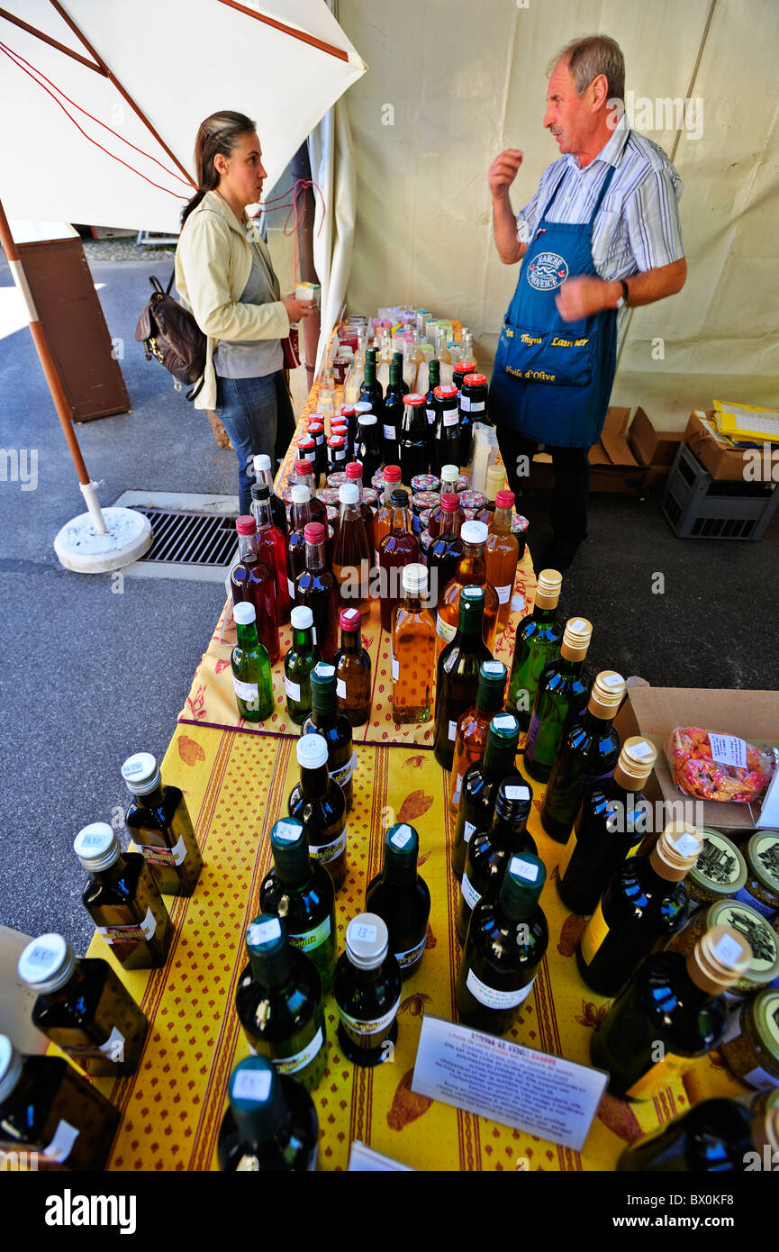 Mercato svizzero in stallo. Un commerciante di strada parla a un cliente. Focus sulle bottiglie che ha in vendita. Foto Stock