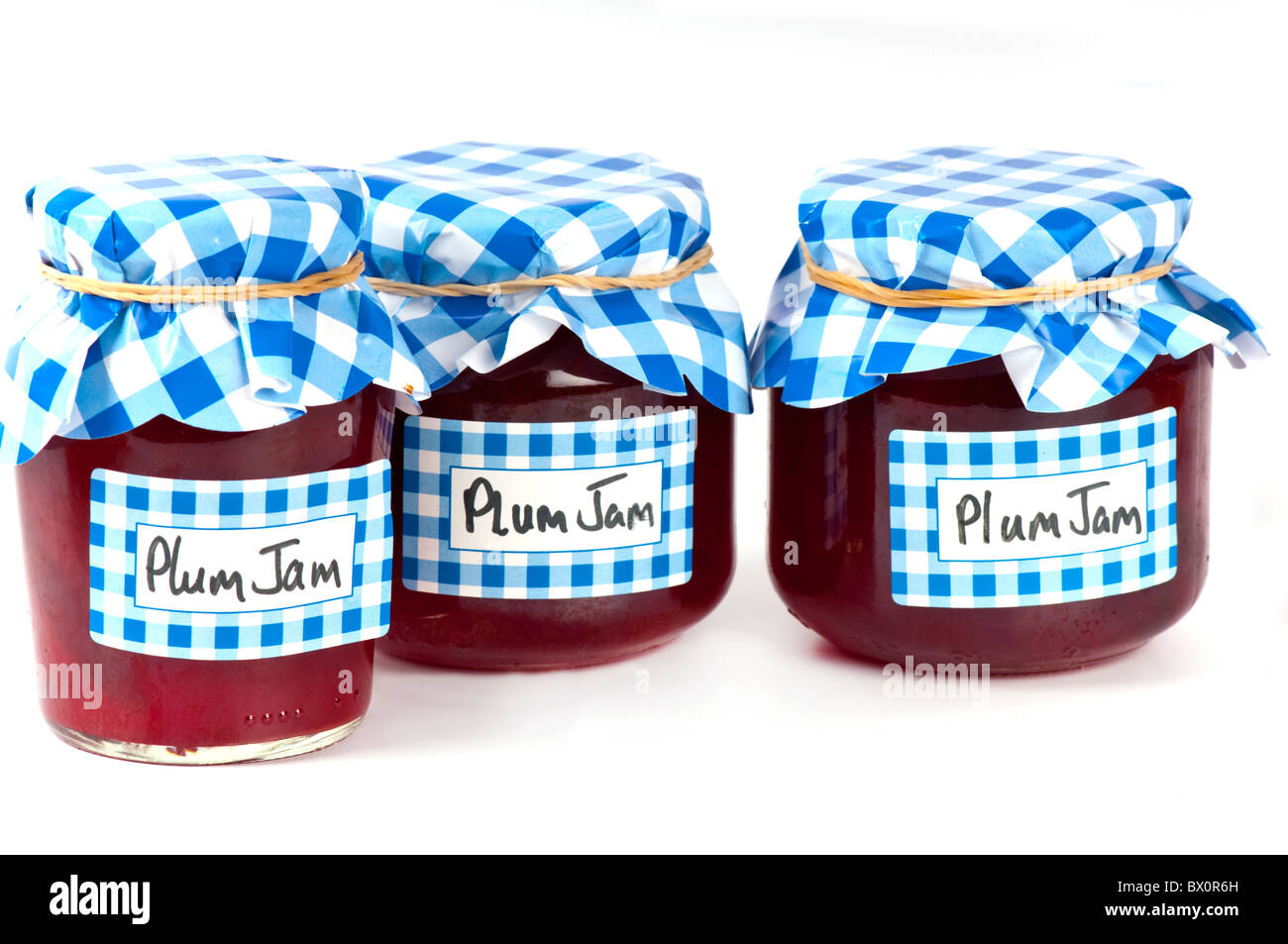 Home fatta di marmellata di prugne in vasi di vetro con selezionata la carta blu coperchio e scritto a mano le etichette. su bianco. Foto Stock