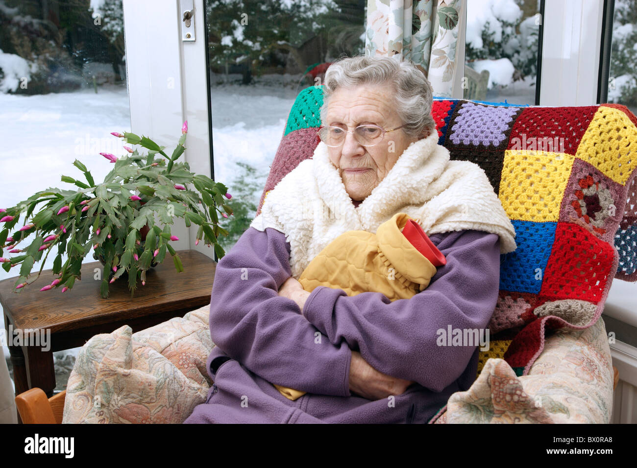 Donna anziana mantenendo calda in inverno avvolto con una coperta di vello  & bottiglie di acqua calda in condizioni di neve Foto stock - Alamy