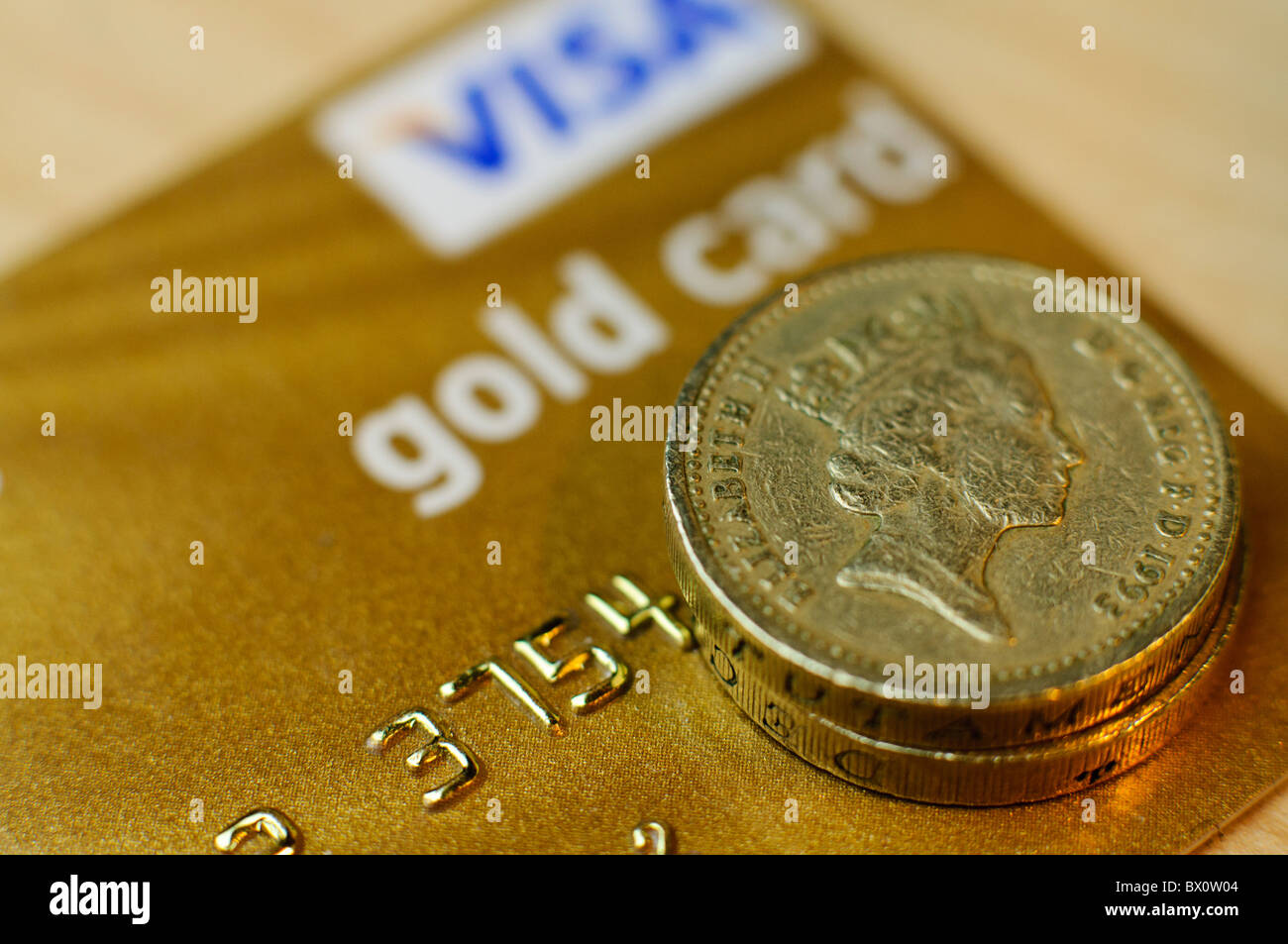 Pound monete sulla parte superiore di una Visa Gold Card carta di credito Foto Stock