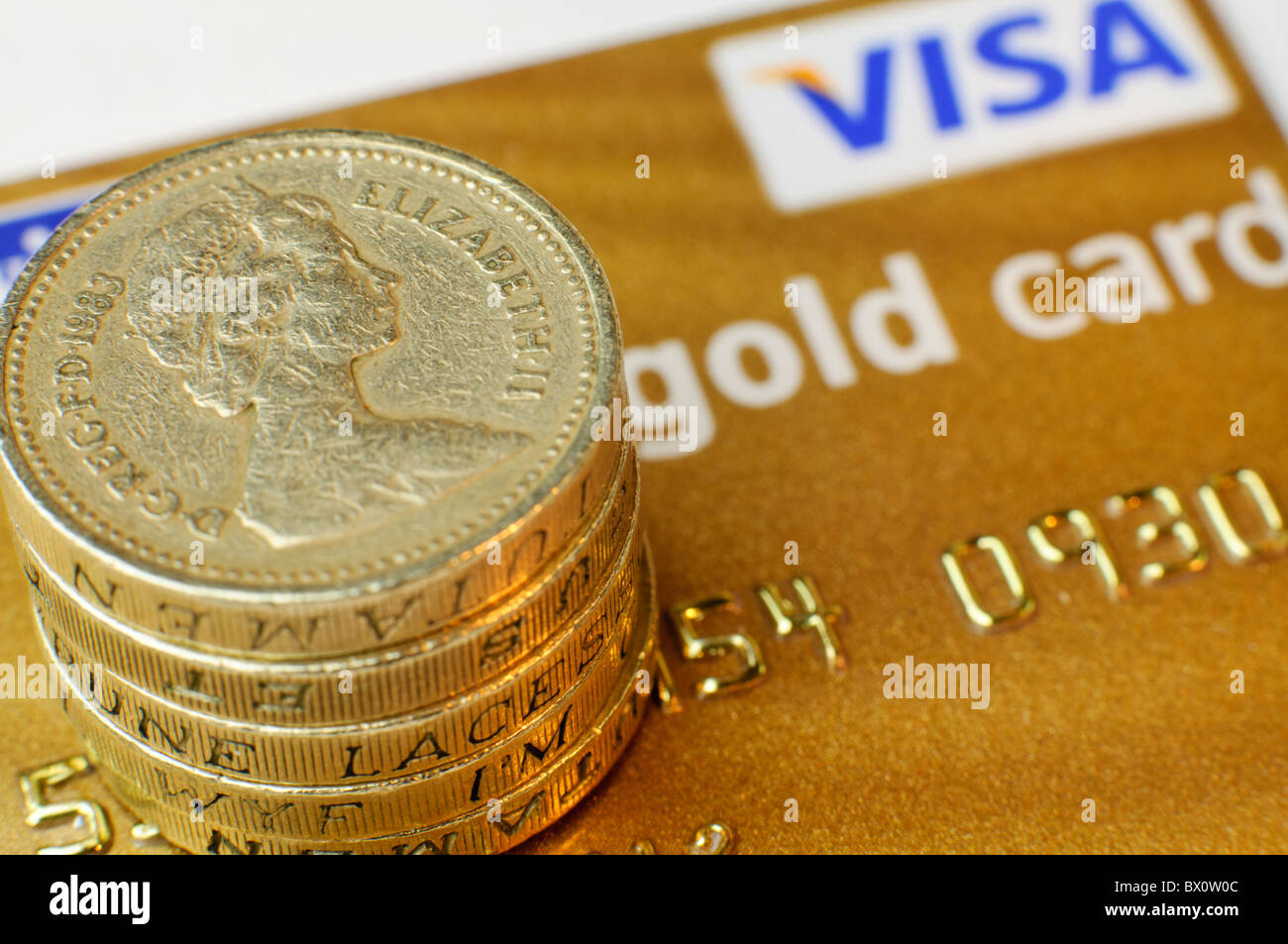 Pound monete sulla parte superiore di una Visa Gold Card carta di credito Foto Stock