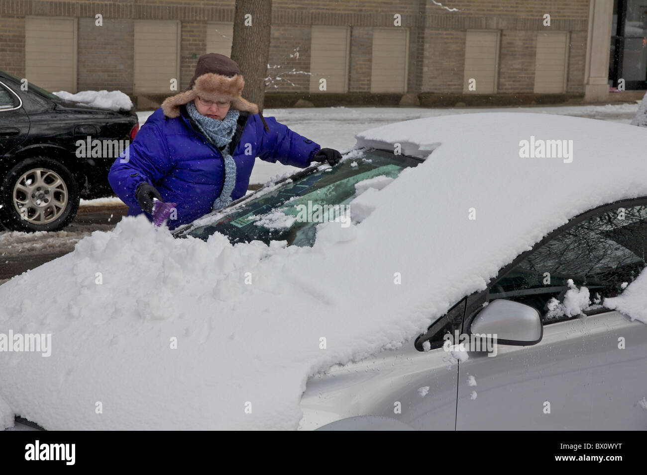 La donna la rimozione di neve dal parabrezza per auto. Foto Stock