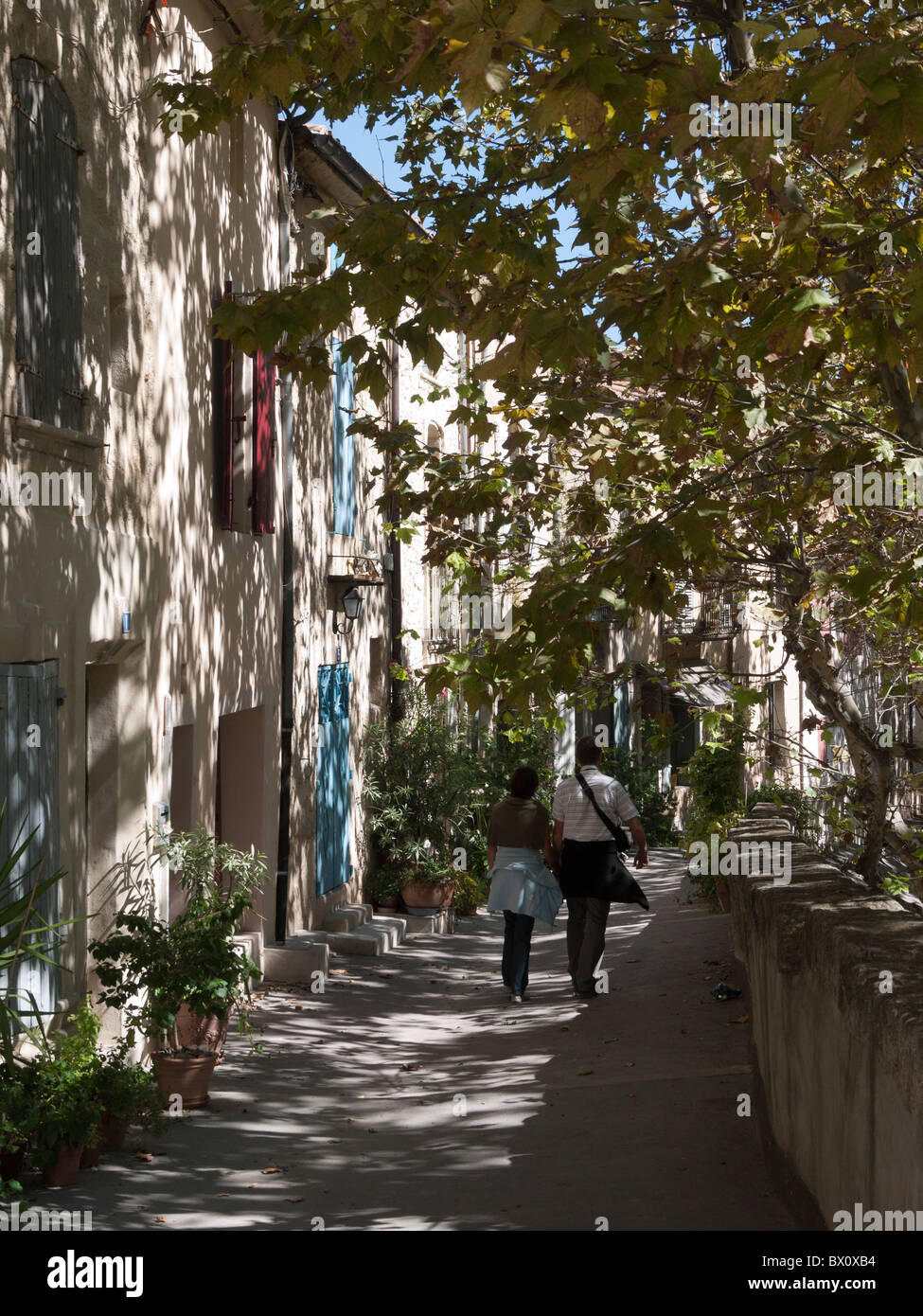 Un paio di camminare mano nella mano lungo un sun pezzata percorso in UZES, Francia Foto Stock