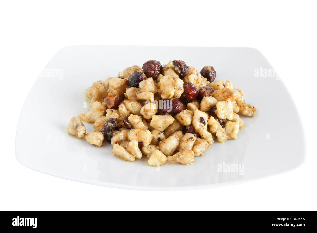 Piastra con pollo e dadi isolato su sfondo bianco con tracciato di ritaglio Foto Stock