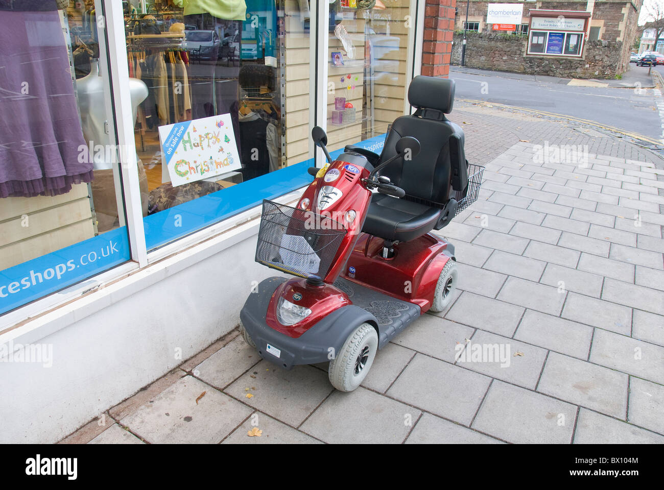 Mobilità elettrica scooter al di fuori del negozio di carità, England, Regno Unito Foto Stock