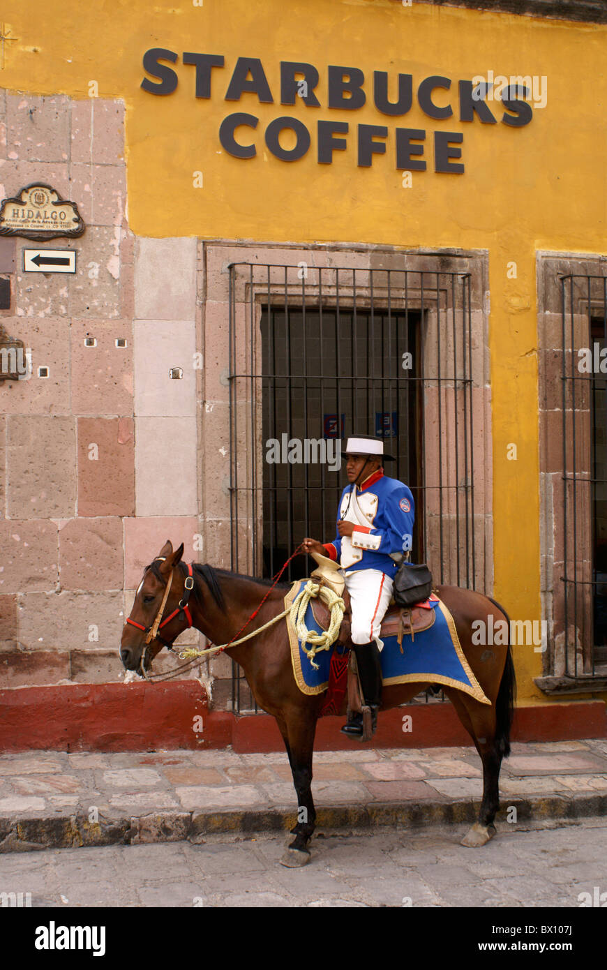 Poliziotto spagnolo in costume traditionlal a cavallo al di fuori di Starbucks Coffee shop in San Miguel De Allende, gentrification,americanization del Messico. Foto Stock