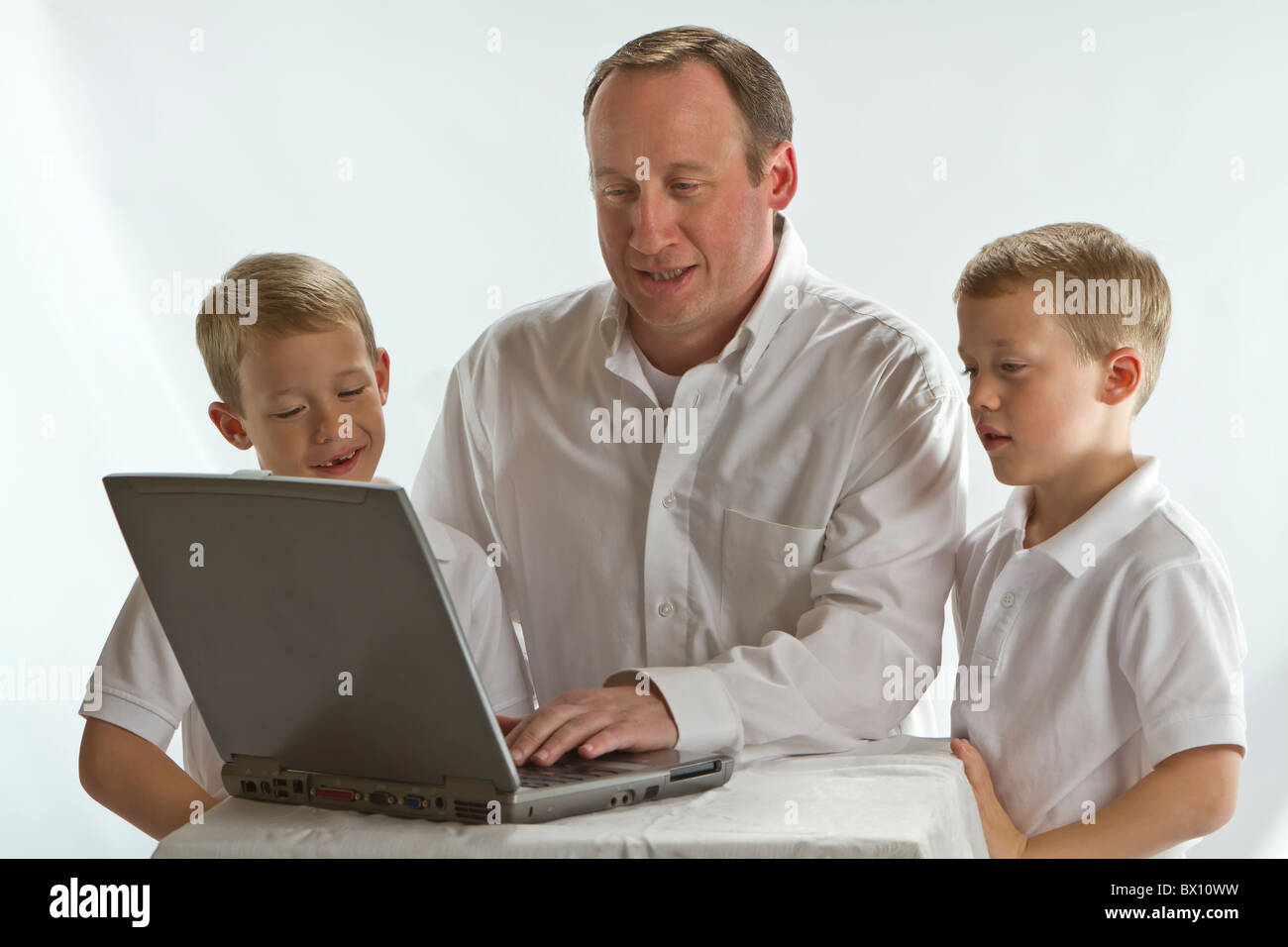 Papà moderno insegnamento sua 6 anni i ragazzi come utilizzare il computer portatile Foto Stock