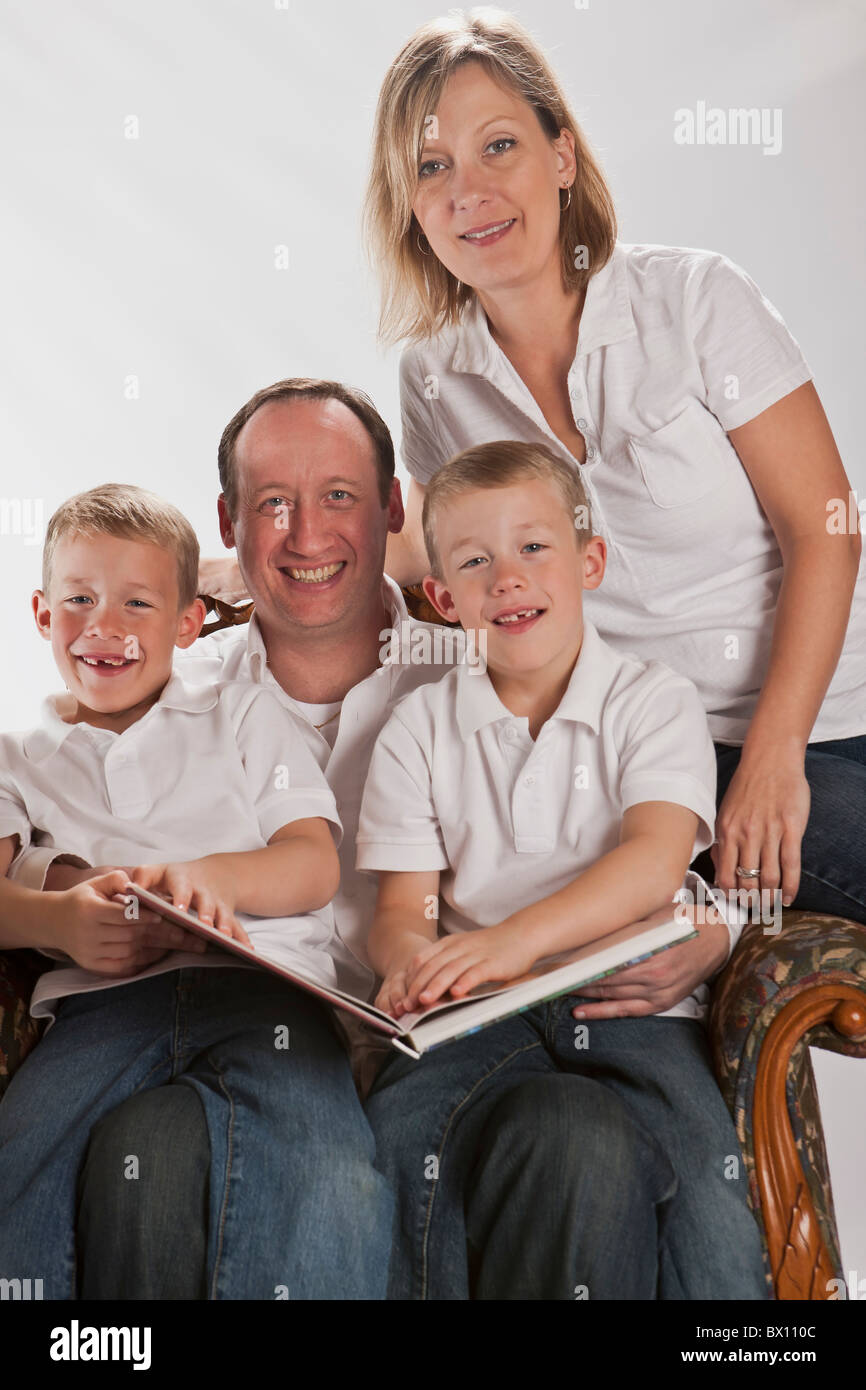 Famiglia moderna facendo i compiti con 6 anni gemelli identici la lettura Foto Stock