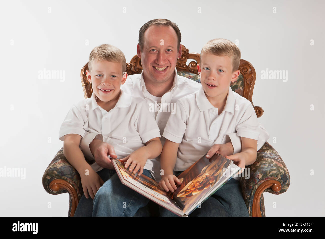 Papà moderno la lettura di un libro con i suoi 6 anni gemelli identici Foto Stock