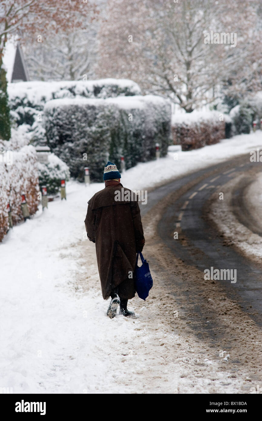 Uomo che cammina dopo lo shopping in Inghilterra dopo la prima nevicata dell'anno. Foto Stock