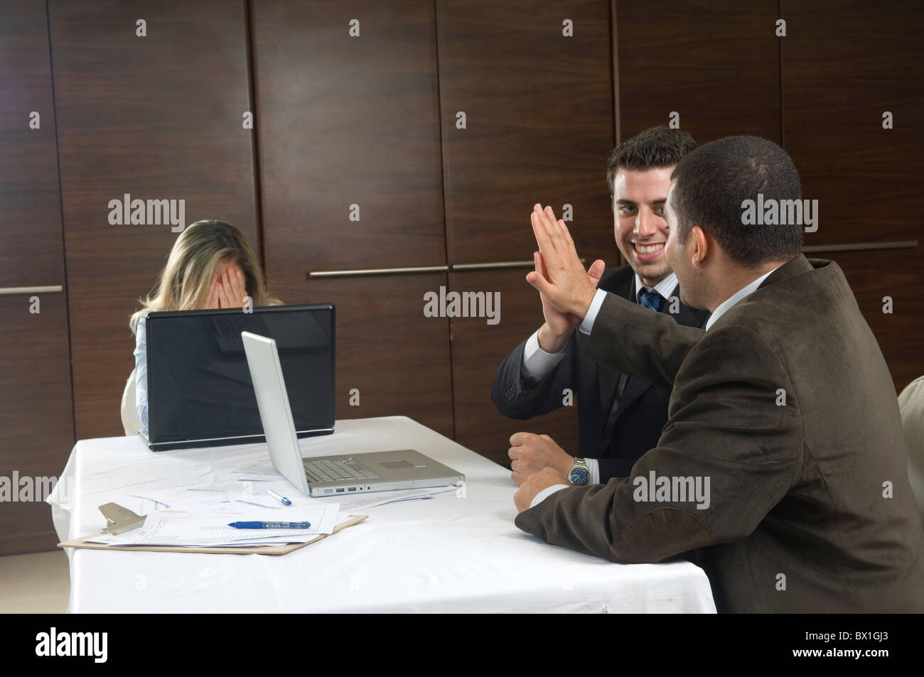 Frustrati business donna testa in mani e due uomini ad alta cinque all'interno di office Beirut Libano Medio Oriente Foto Stock