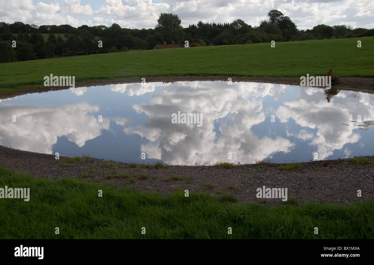 Sky riflesso in uno stagno in un campo nei pressi di Nunney, Somerset, Regno Unito Foto Stock