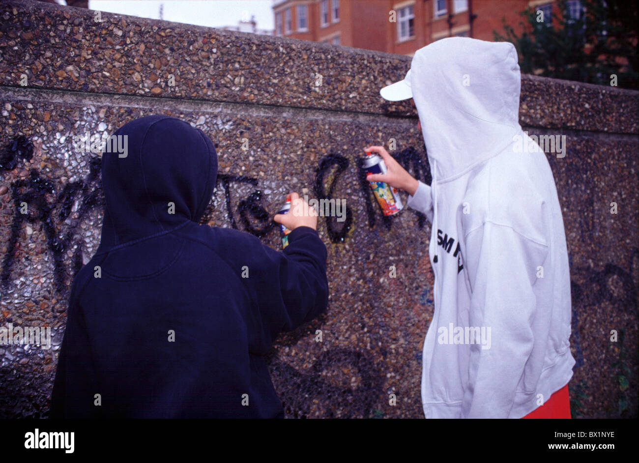 Ragazzo ragazzi limitata Graffiti hip-hop illegale cofano stile di vita sociale degli adolescenti di spray due ragazzi di atti di vandalismo a piedi Foto Stock
