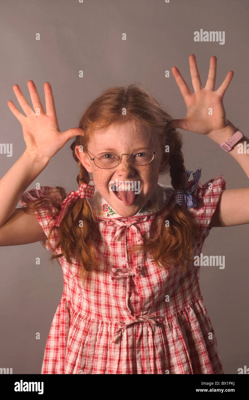Trecce bambino lentiggini gesto ragazza bicchieri grimace umorismo ritratto rosso capelli Capelli rossi picaro studio Foto Stock