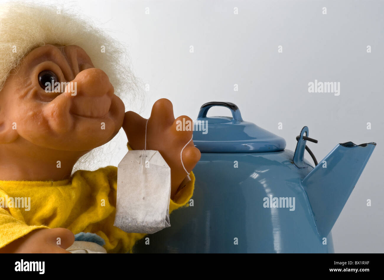 Nonna troll tenendo in mano un teabag con teakettle in background. È pronta a preparare il tè. Spazio di copia. Foto Stock