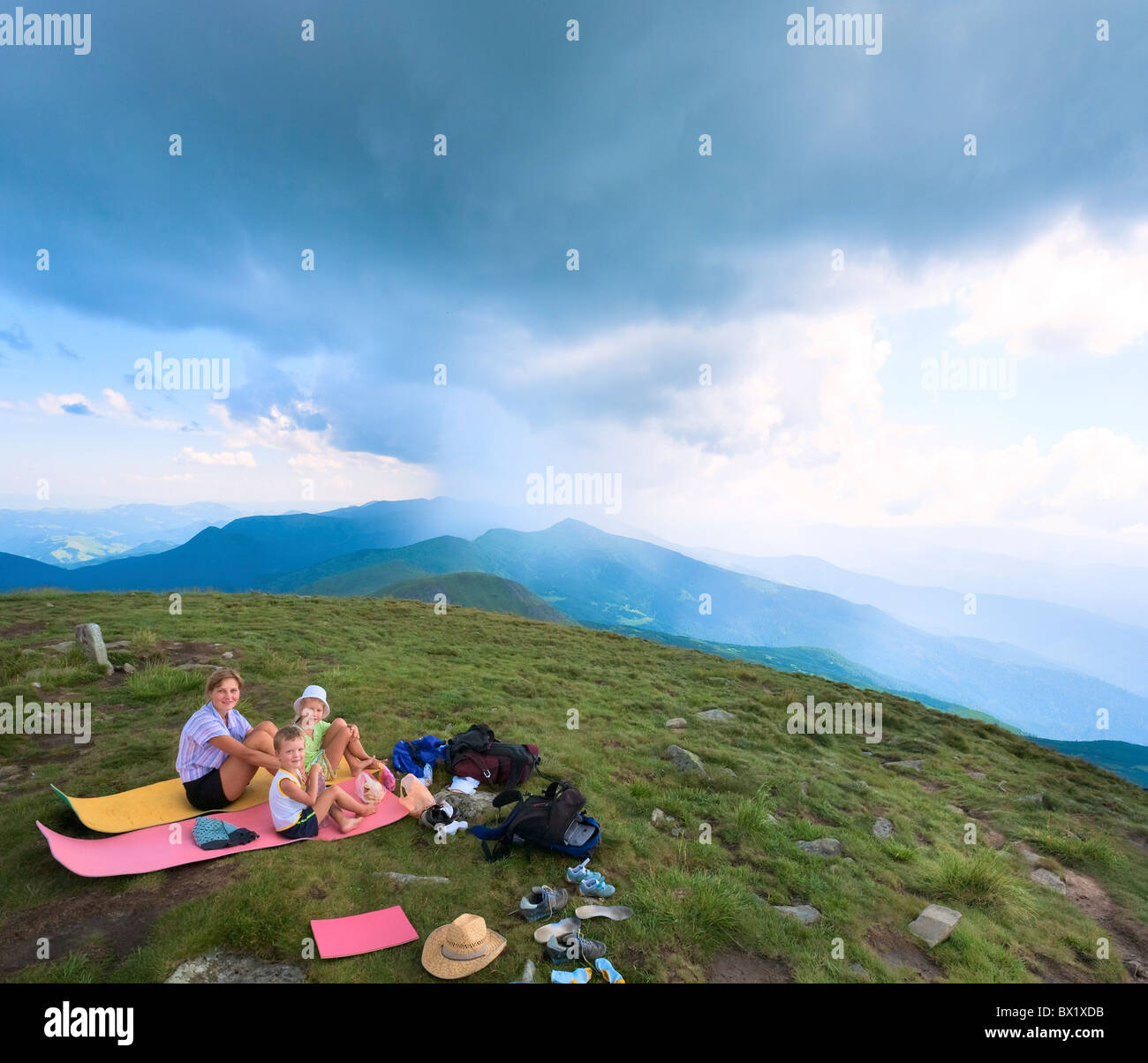 Famiglia in appoggio su un estate mountain top e temporale nella distanza (Goverla Mount, Ucraina) Foto Stock