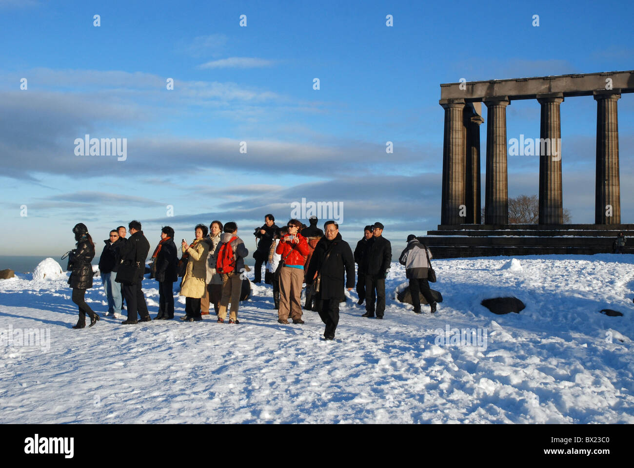 Un gruppo di turisti scattare fotografie presso il monumento nazionale su Calton Hill a Edimburgo dopo un inizio di dicembre nevicata. Foto Stock