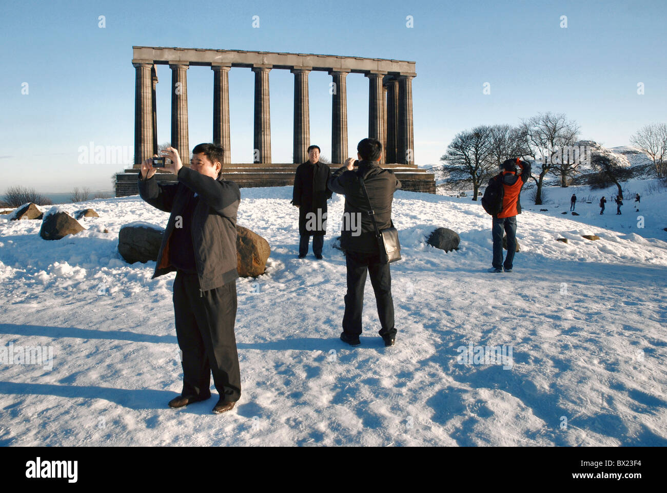 I turisti scattare fotografie presso il monumento nazionale su Calton Hill a Edimburgo dopo un inizio di dicembre nevicata. Foto Stock