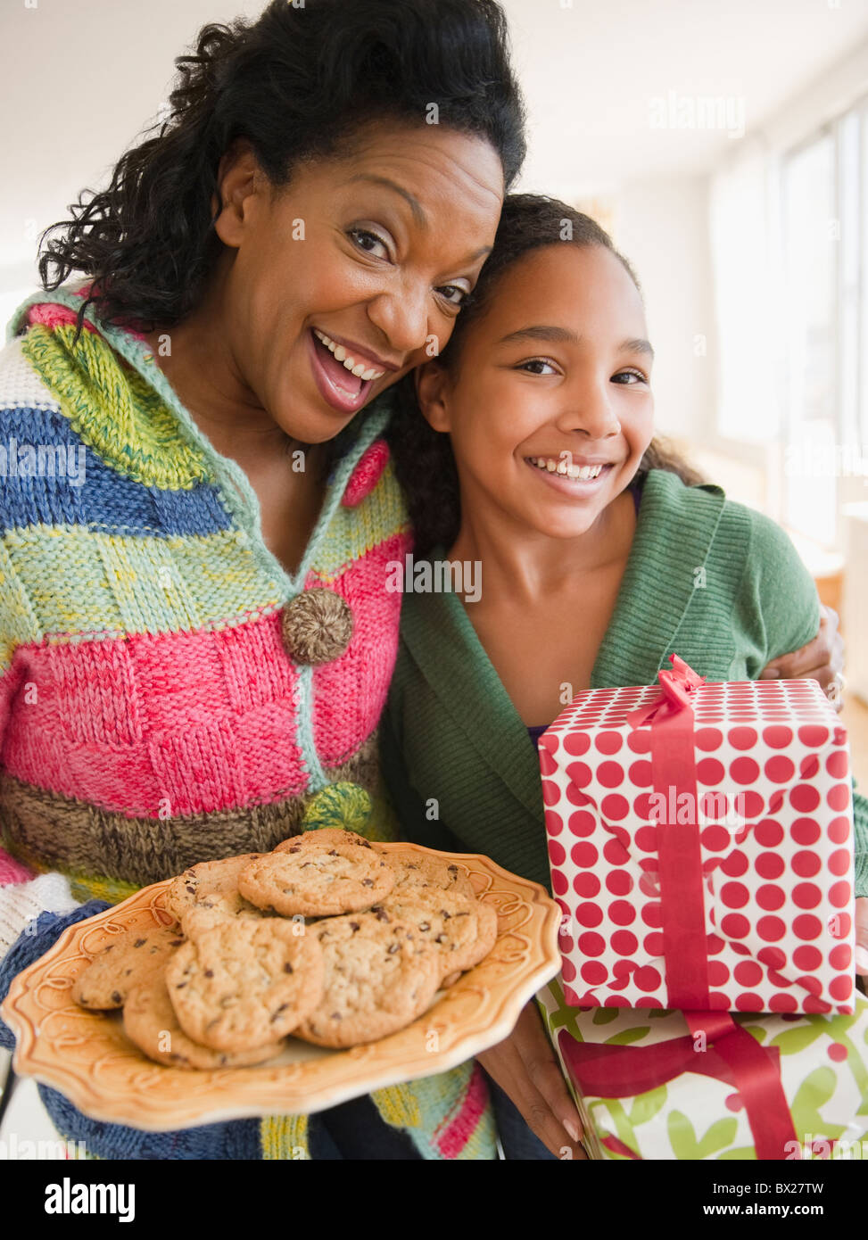 Madre e figlia che trasportano regalo di compleanno e cookie Foto Stock