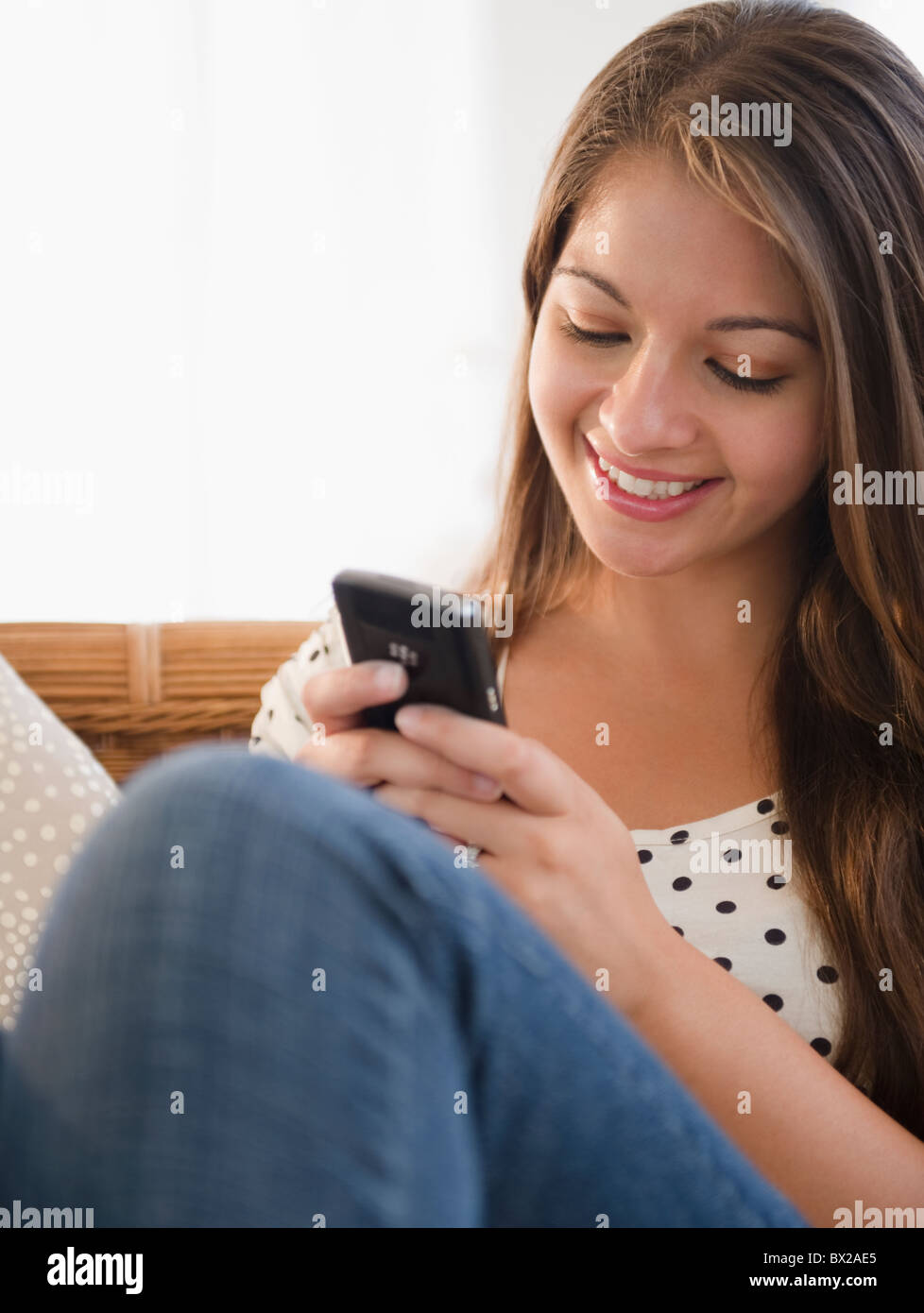 Sorridente donna indiana per la messaggistica di testo sul telefono cellulare Foto Stock