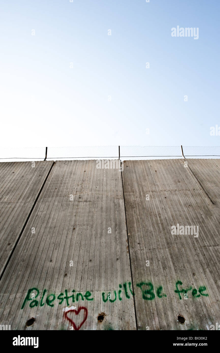 Il graffiti slogan "Palestina sarà gratuita' è dipinta sulla separazione israeliano della barriera 8 metro di altezza parete di cemento. Foto Stock