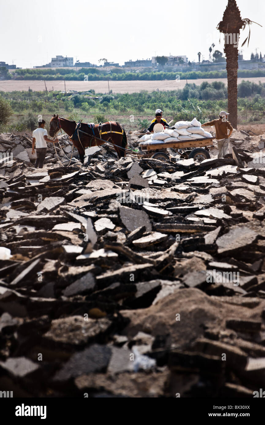 Operai palestinesi raccogliere schiacciato aggregato lapideo da sotto distrutto strade vicino alla striscia di Gaza "no-go' zona di confine. Foto Stock