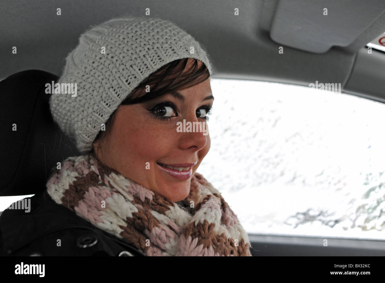 Giovane donna lampeggia grandi occhi in telecamera indossando lanosi beret style hat Foto Stock