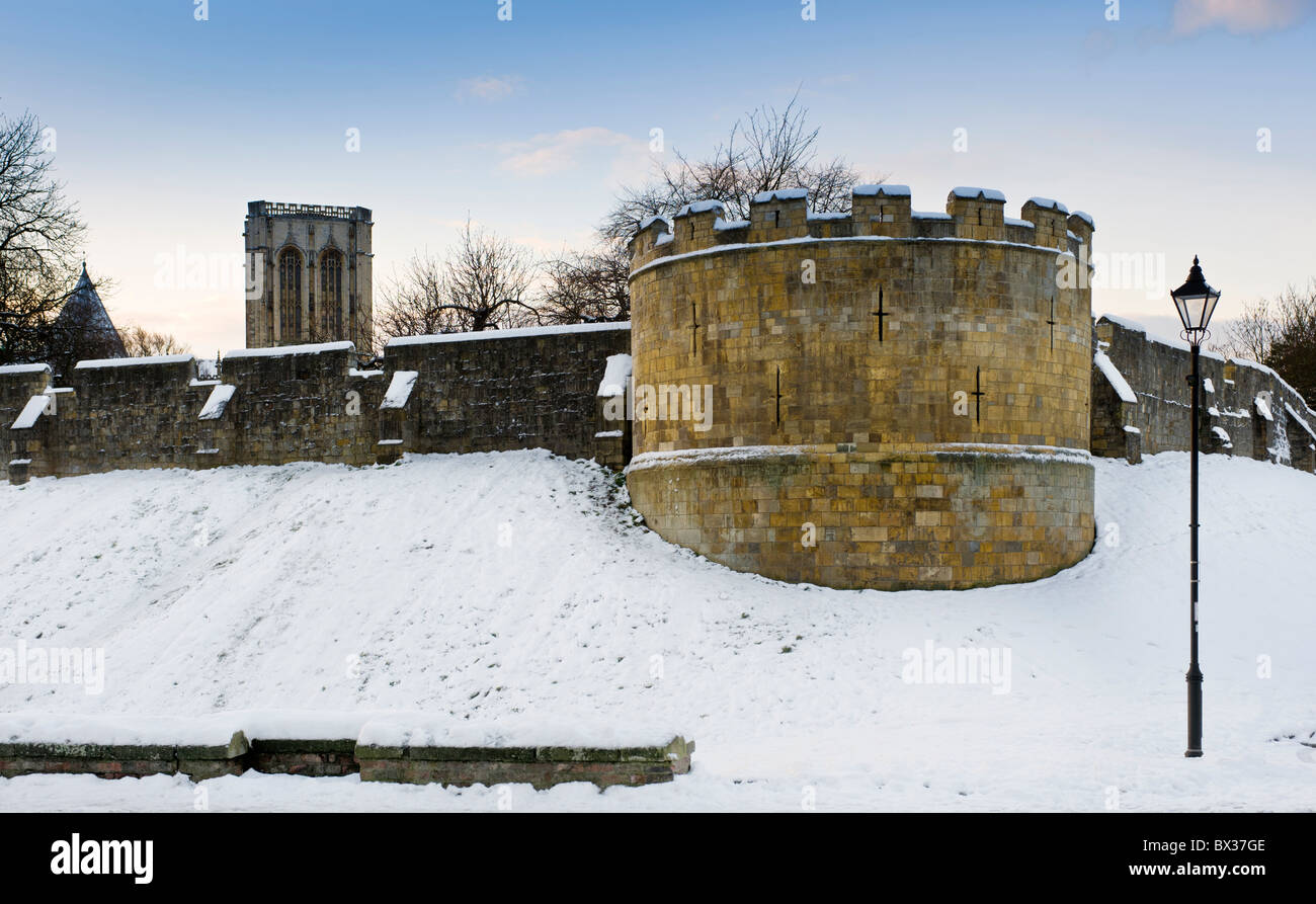 Robin Hood Tower coperto di neve e le mura della città con la torre centrale di York Minster dietro, Lord Mayor's Walk, York, Regno Unito Foto Stock
