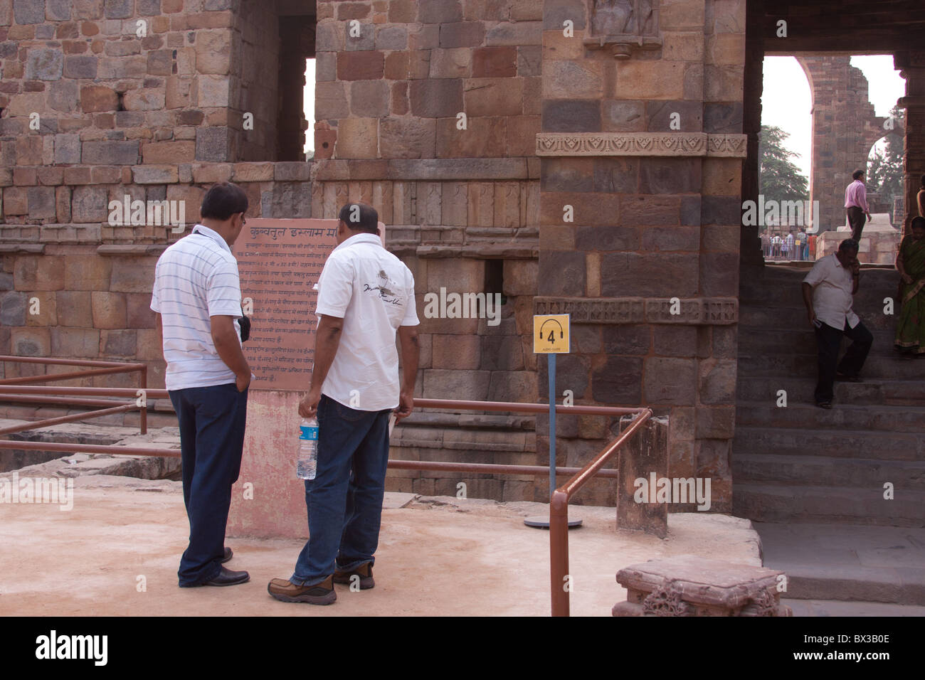 I turisti la lettura di un segno all'interno del Qutub Minar complesso in New Delhi, India. Tour Audio segno con operazioni in background Foto Stock