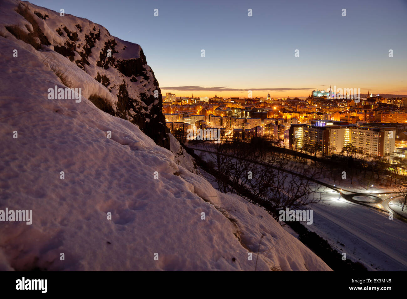 Guardando verso il basso su Edimburgo al tramonto dalla coperta di neve Salisbury Crags Foto Stock