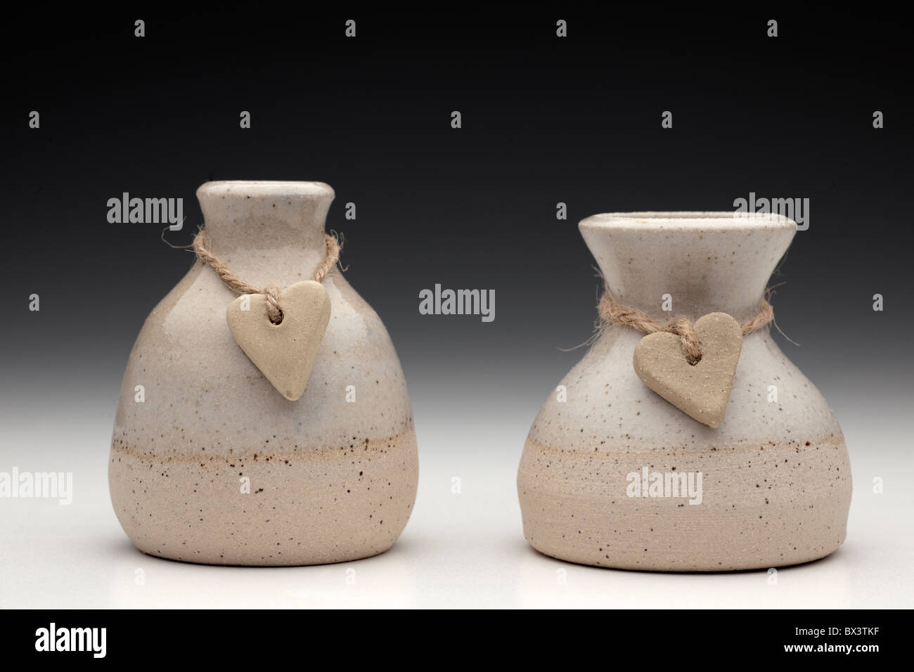 Due cuori di pietra sul filo avvolto intorno a due vasi di ceramica Foto Stock