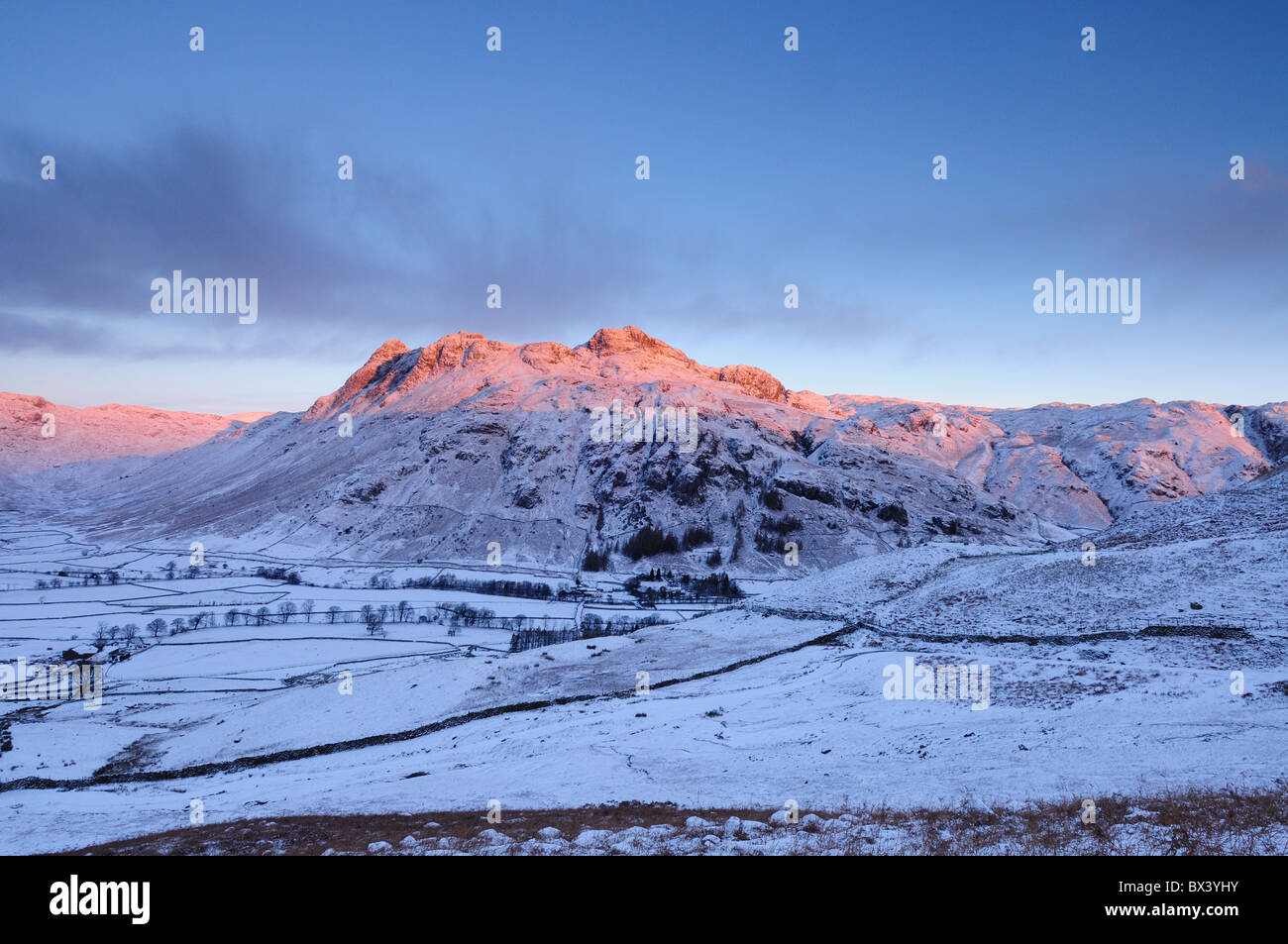 Alba invernale sole rosa su The Langdale Pikes nel Lake District inglese Foto Stock