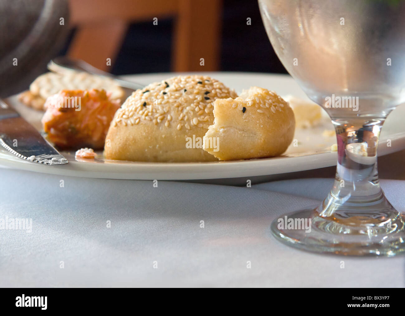 Avanzi di pane su un piatto finito di cibo con un vetro d'acqua Foto Stock