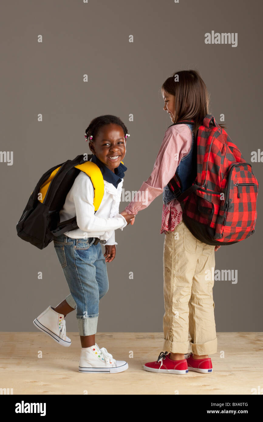 Due ragazze con zaini tenendo le mani Foto Stock