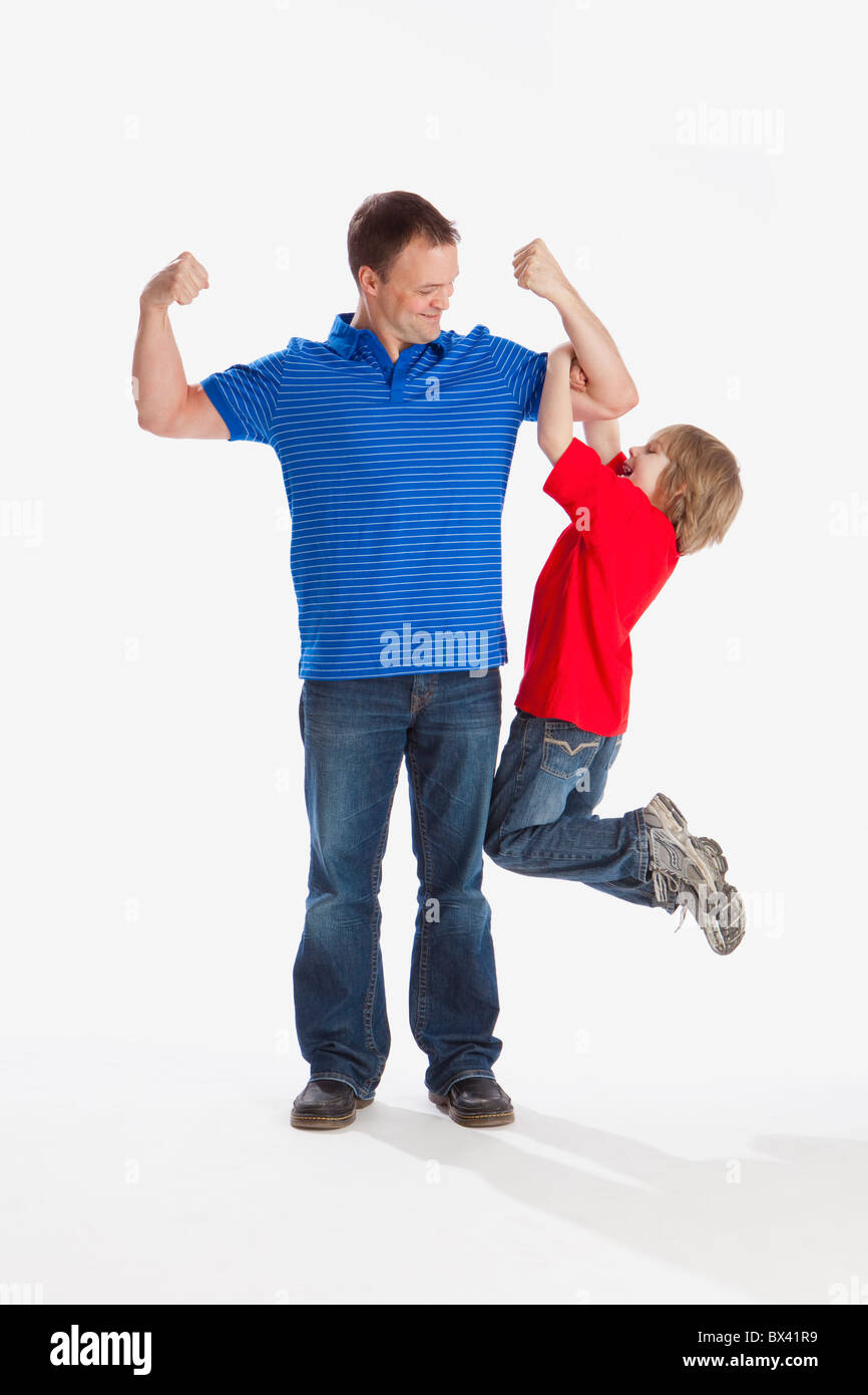 Un figlio appeso fuori il suo padre come egli si flette i suoi muscoli Foto Stock