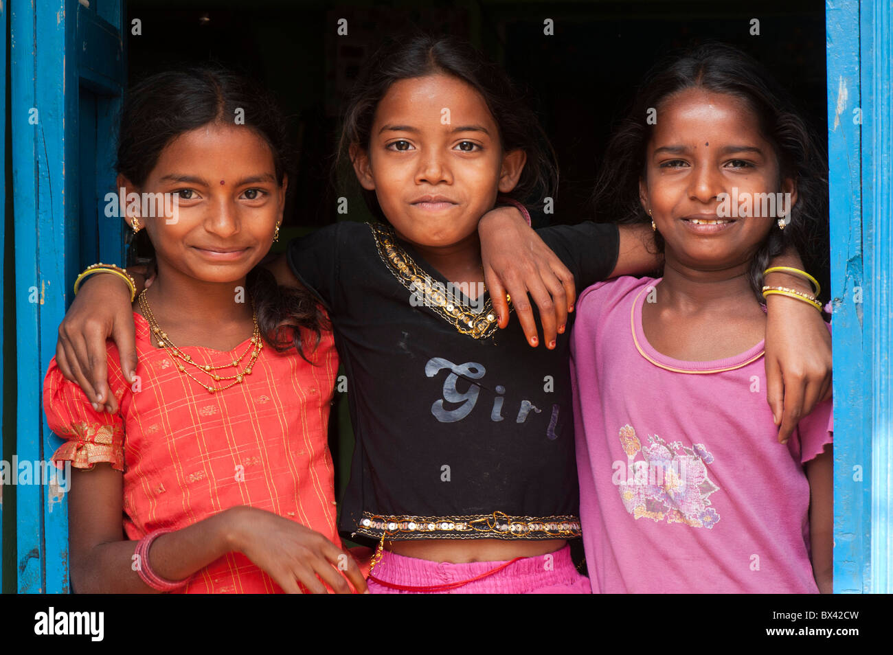 Sorridendo felice villaggio indiano ragazze abbracciando alla porta di casa loro. Andhra Pradesh, India Foto Stock