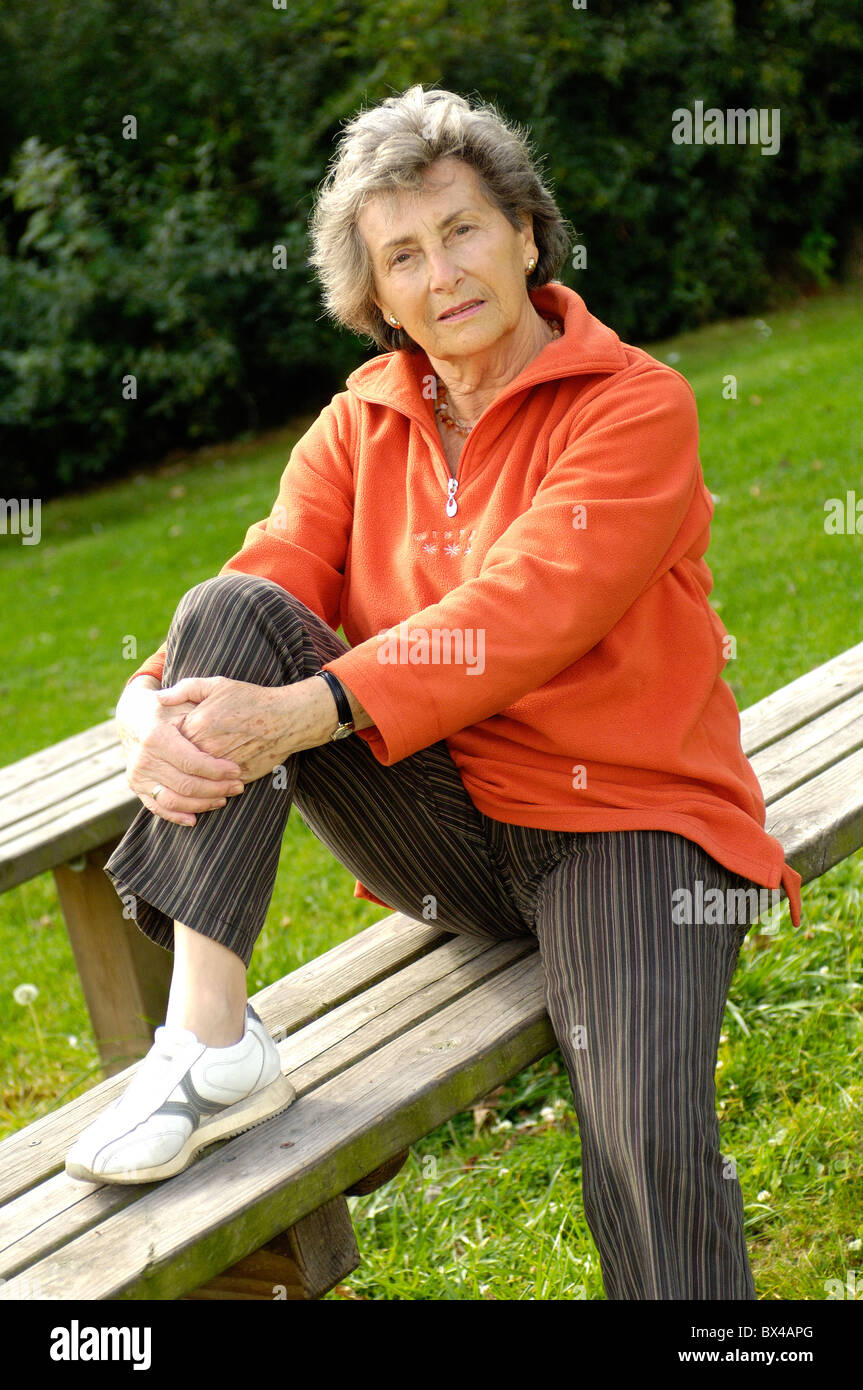 Donna anziana sul parco giochi per bambini Foto Stock