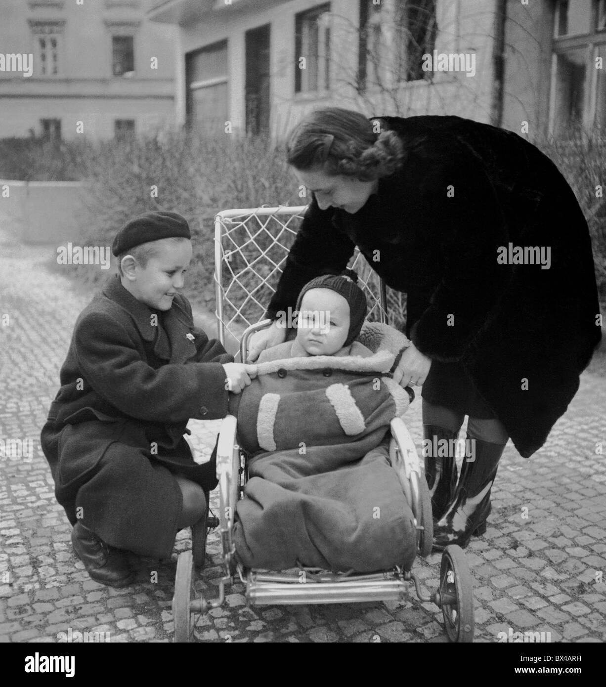 Praga, 1950. La madre aiuta il bambino nel passeggino con l aiuto di suo figlio. CTK Vintage foto Foto Stock