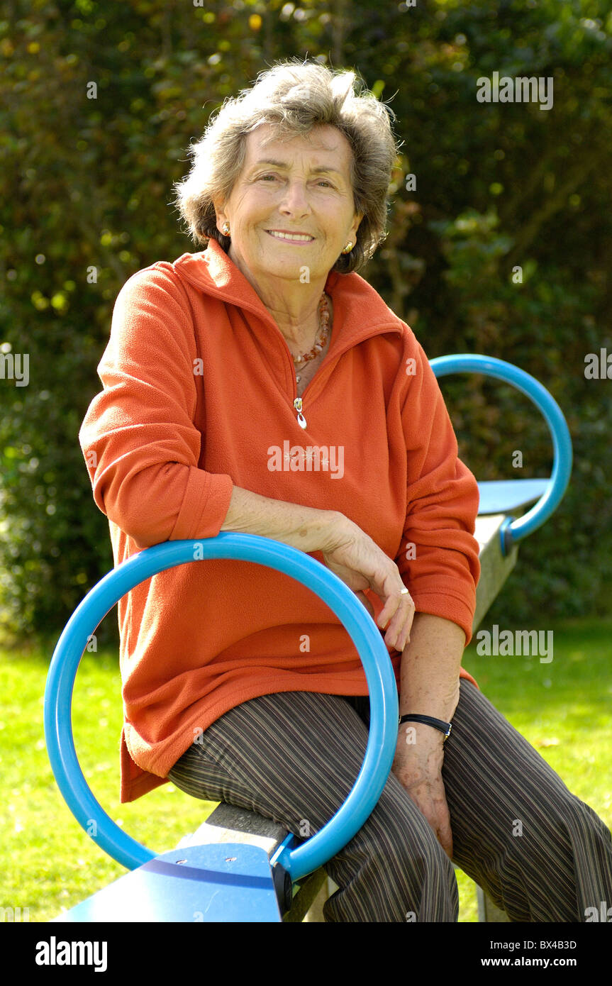Donna anziana sul parco giochi per bambini Foto Stock