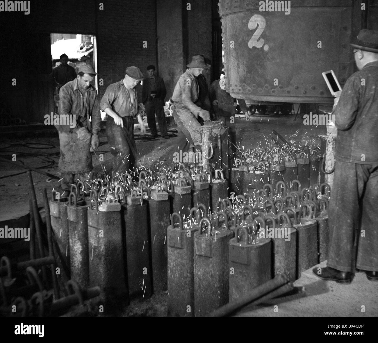 La Cecoslovacchia - la maggior parte, 1950. I lavoratori del ferro a riempire moduli di lingotti di acciaio fuso a impianto siderurgico. CTK Vintage foto Foto Stock