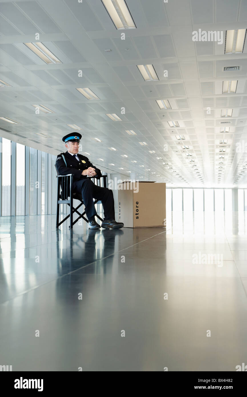 Guardia in uniforme seduto nel vuoto dello spazio ufficio Foto Stock