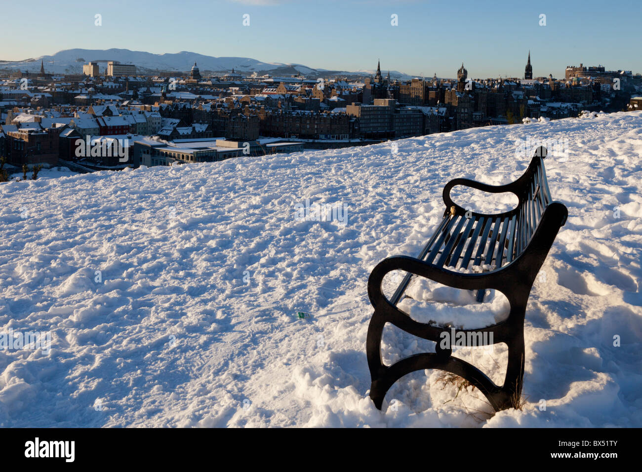 Banco vuoto in inizio di mattina di sole su un snowy Calton Hill, si affacciano su di Edimburgo, Scozia, Regno Unito Foto Stock