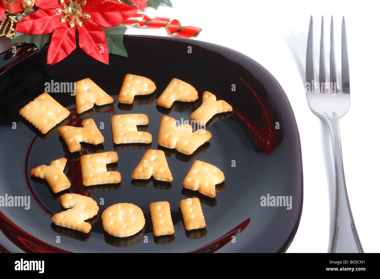 La piastra nera con carattere di biscotti a forma di forcella e l anno nuovo decorazione isolato su bianco Foto Stock