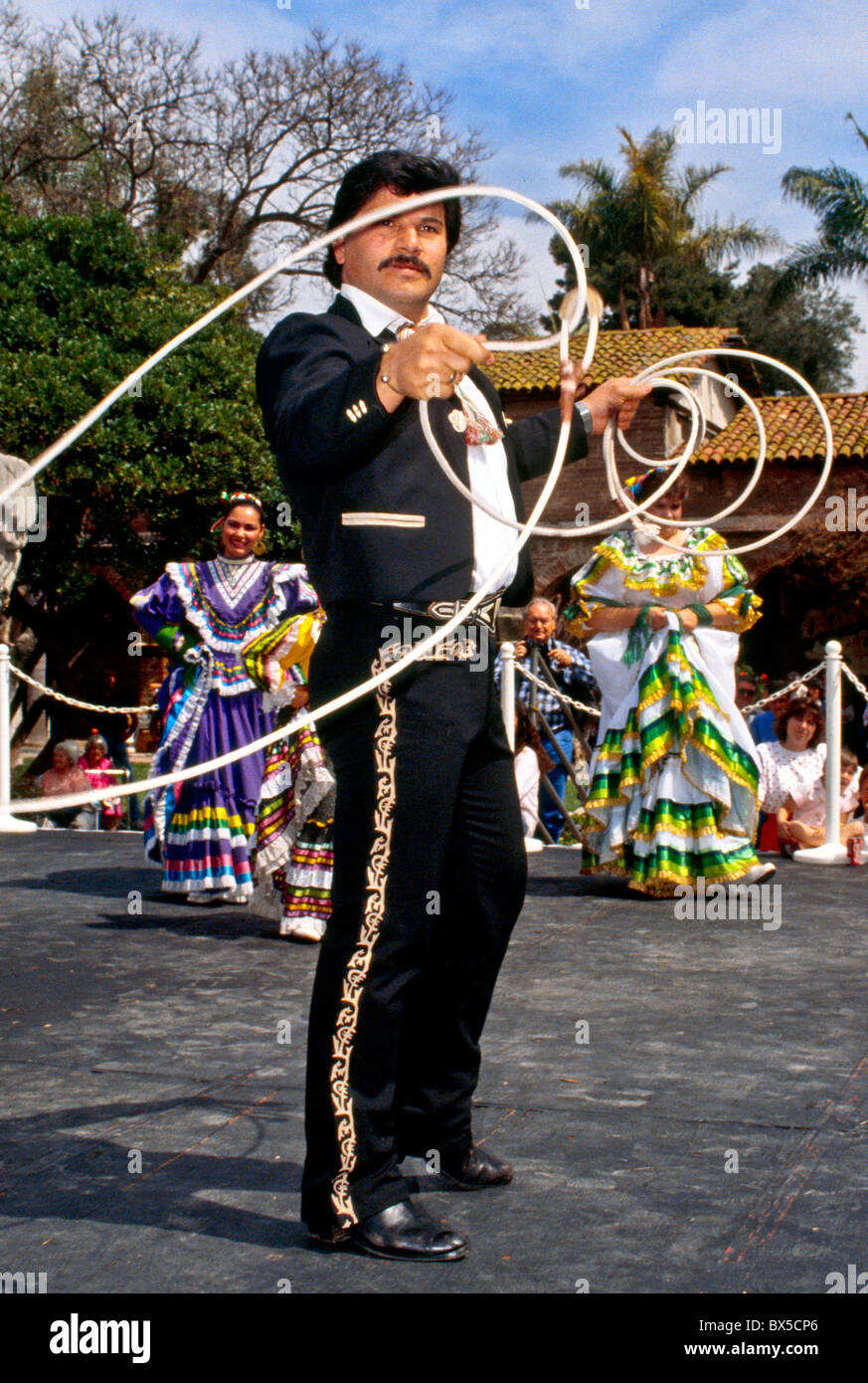 Un messicano di ballerini folk esegue una danza lariat usando un lazo a California folk festival. Nota le donne in costume nativo. Foto Stock