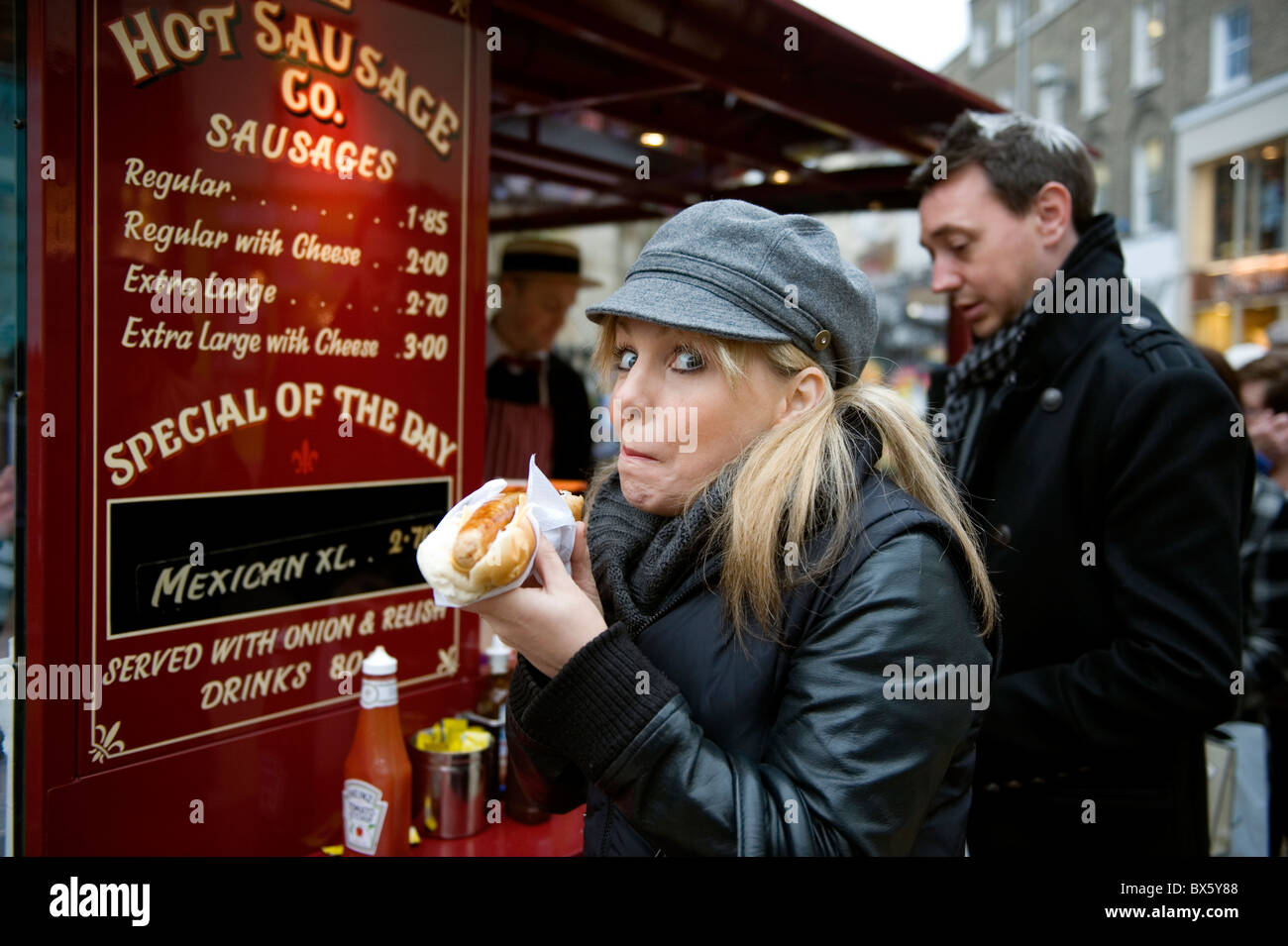 Cambridge, Gran Bretagna. Donna di mangiare salcicce calde in un rotolo di cibo di strada nella città universitaria di Cambridge, Gran Bretagna. Foto Stock