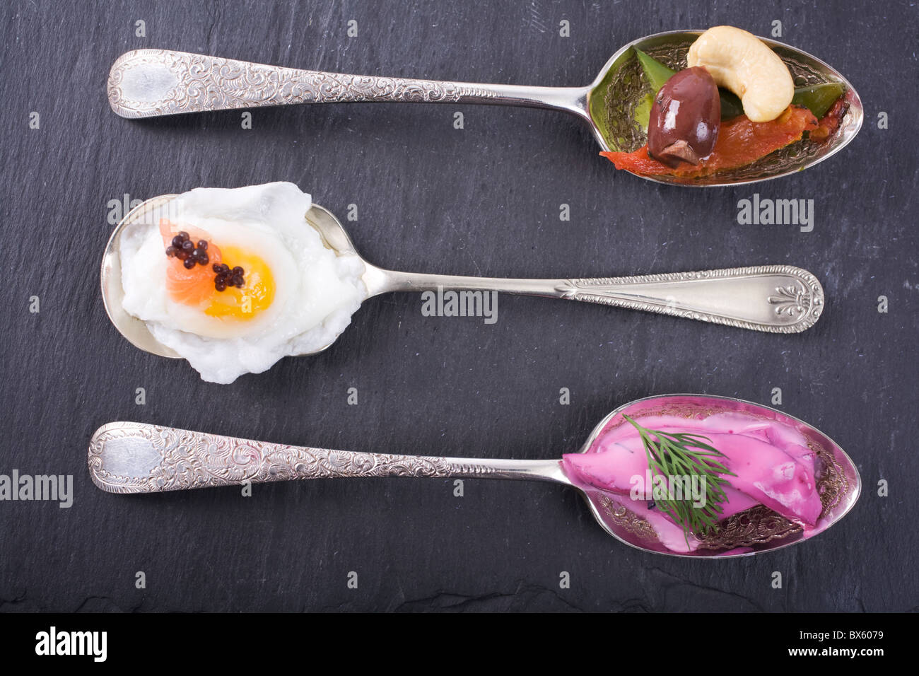Una selezione di antipasti gourmet di argento cucchiai, servita su ardesia. Anacardi, insalata di caviale + uovo e barbabietole + rafano Foto Stock