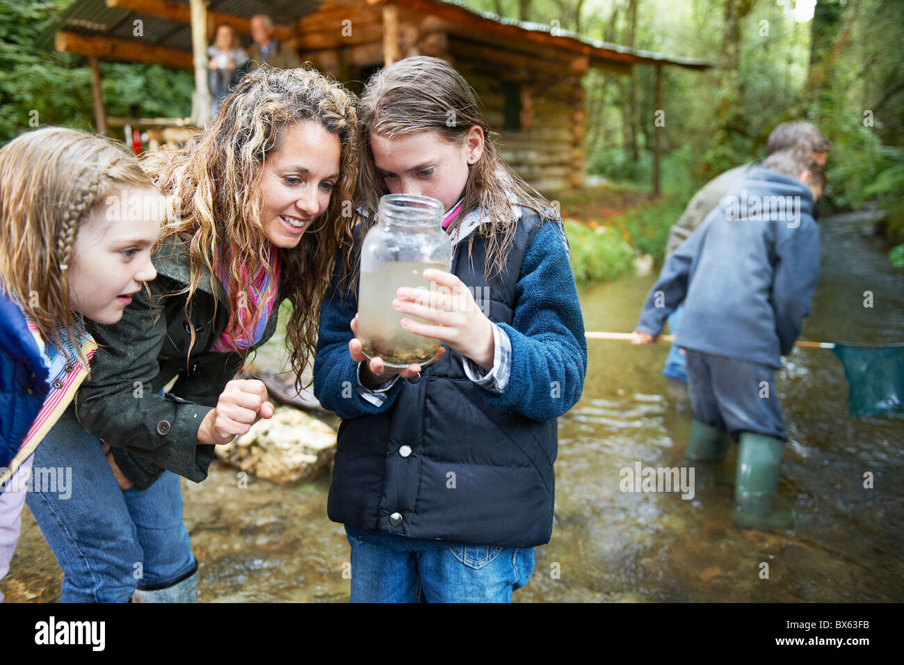 Famiglia in cerca di insetti nel vasetto di marmellata Foto Stock