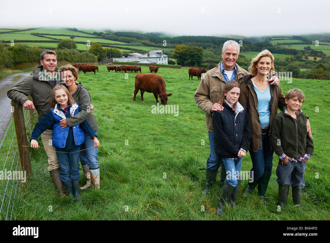Famiglia in fattoria in un campo con le mucche Foto Stock