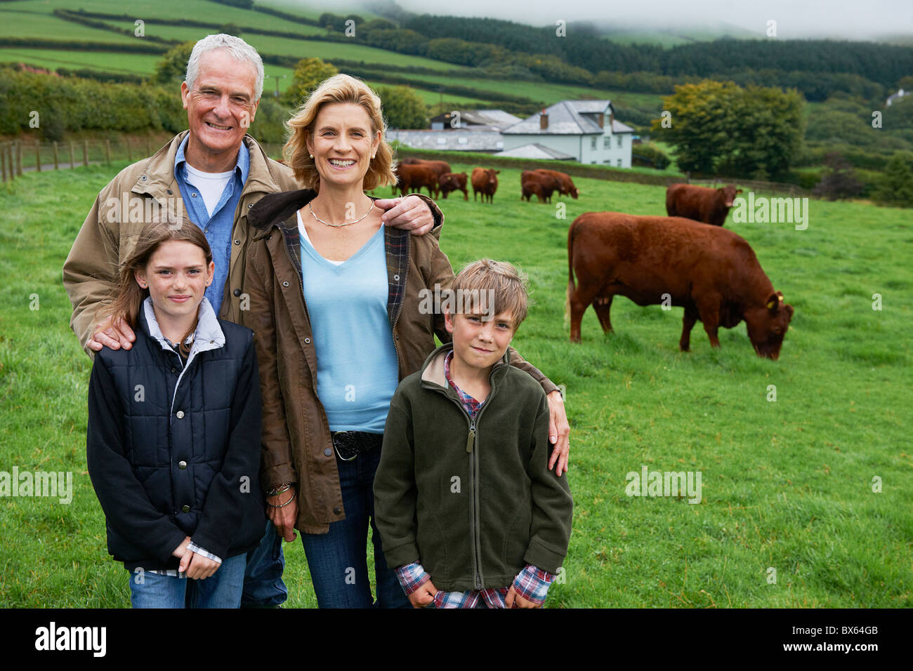 Famiglia in fattoria in un campo con le mucche Foto Stock